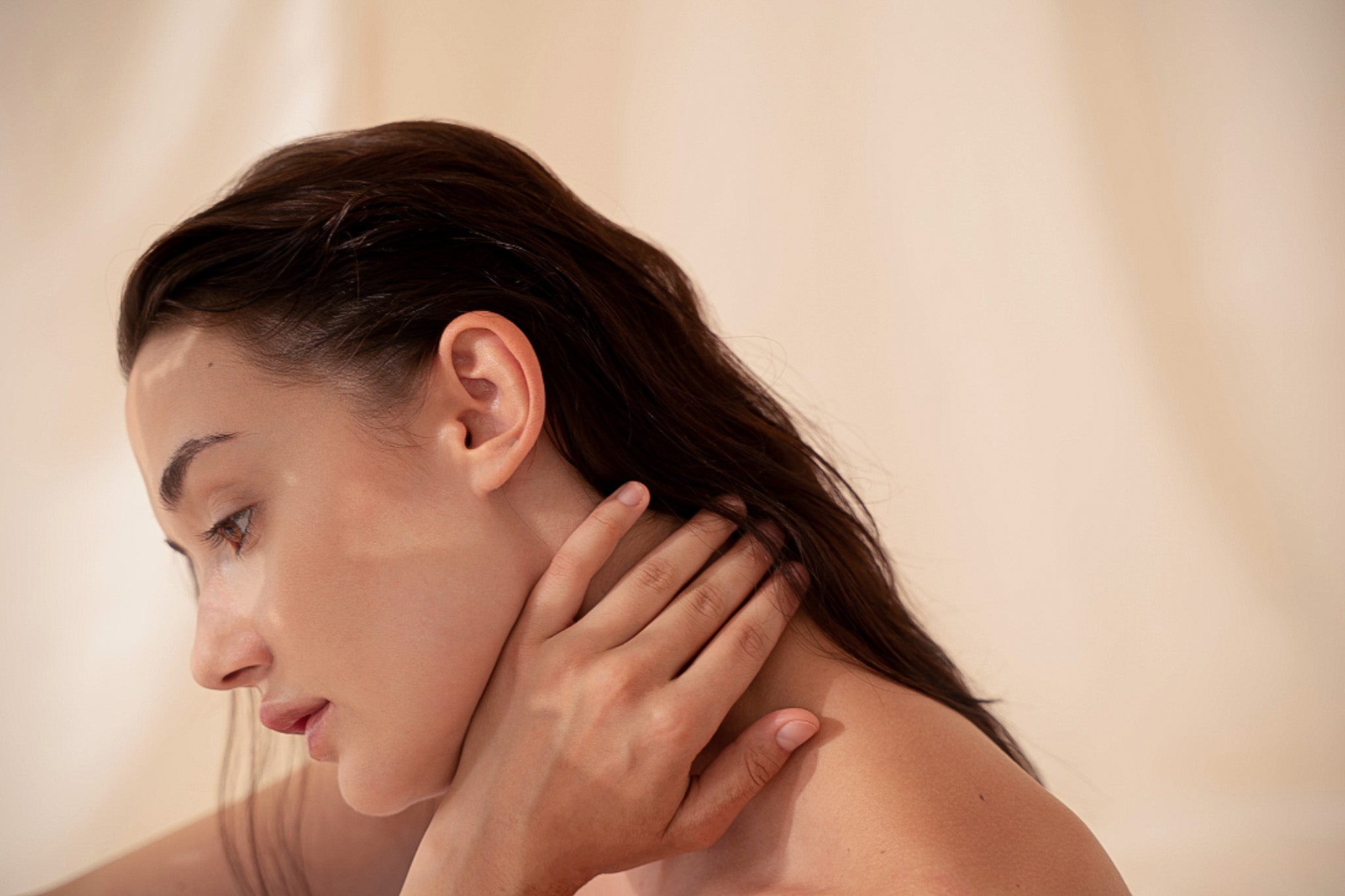 Ragazza dalla pelle nuda che si tocca il collo, simbolo di una skincare consapevole che evita errori per ottenere una pelle sana e luminosa