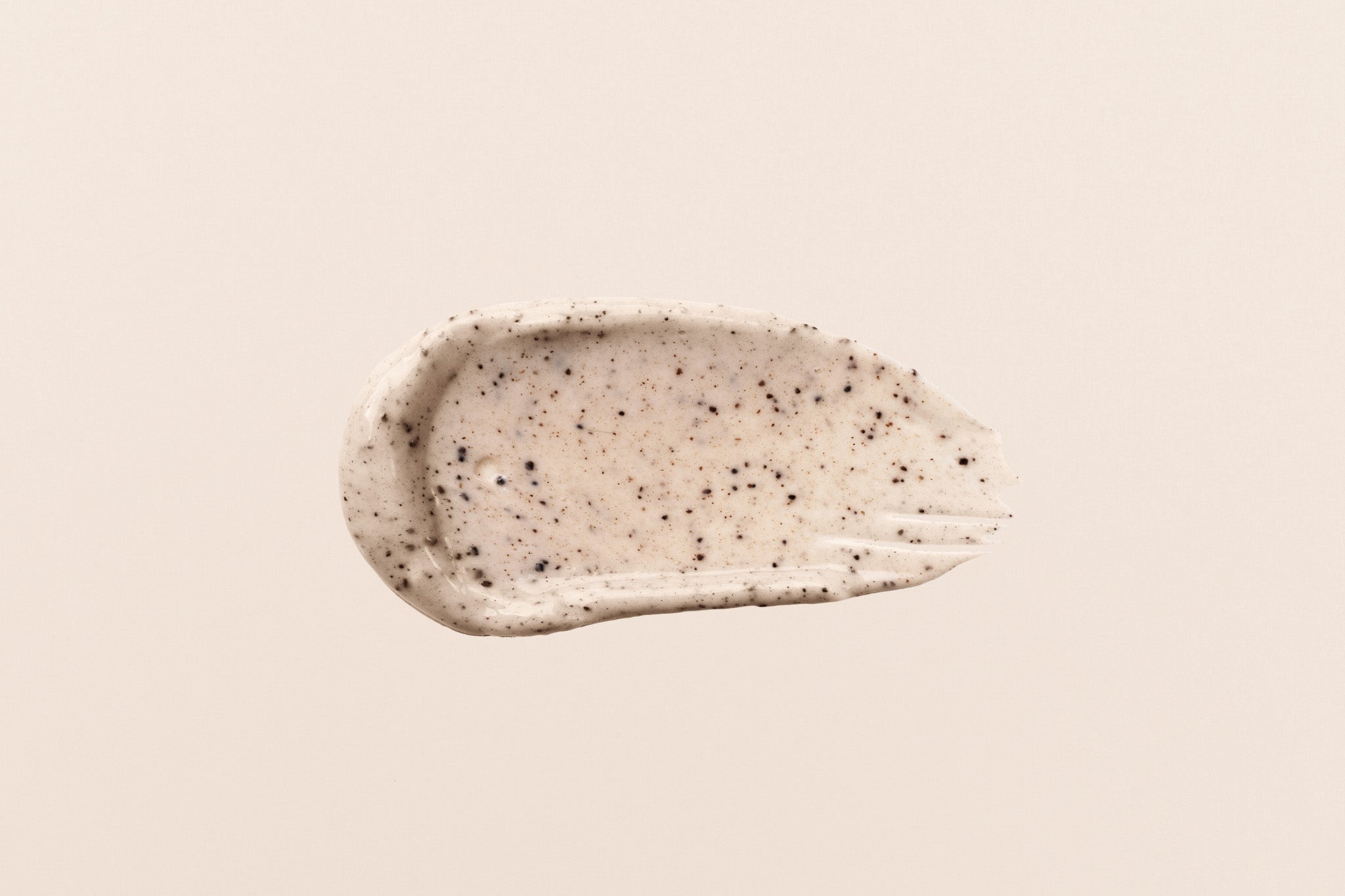 Splash di scrub esfoliante con microgranuli su superficie liscia, ideale per pelle liscia e levigata
