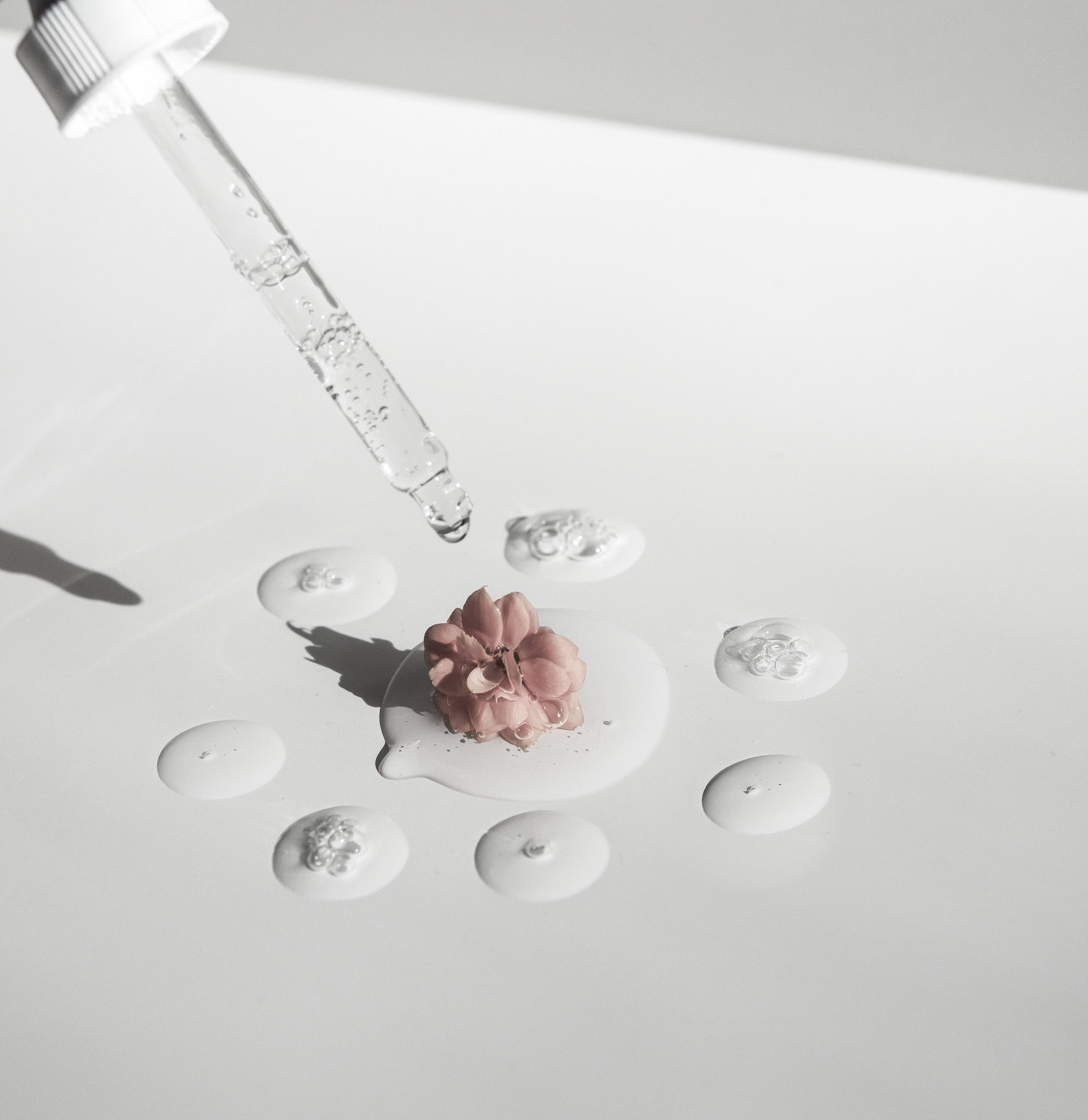 Siero viso Made in Italy che cola da una pipetta su un fiore rosa