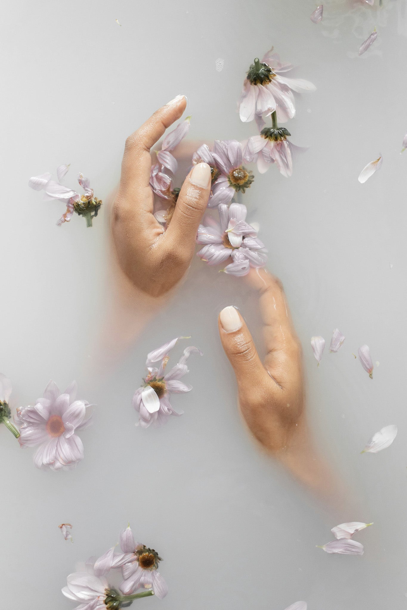Skincare naturale per trattamento di bellezza rappresentato da mani e fiori immersi nell'acqua